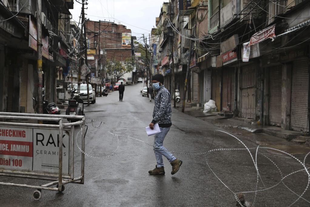 An Indian man wearing a mask walks past a barbed wire erected by authorities as part of enforcing a lockdown as a precautionary measure against COVID-19 in Jammu, India, Tuesday, March 24, 2020. Authorities have gradually started to shutdown much of the country of 1.3 billion people to contain the outbreak. For most people, the new coronavirus causes only mild or moderate symptoms. For some it can cause more severe illness. (AP Photo/Channi Anand)