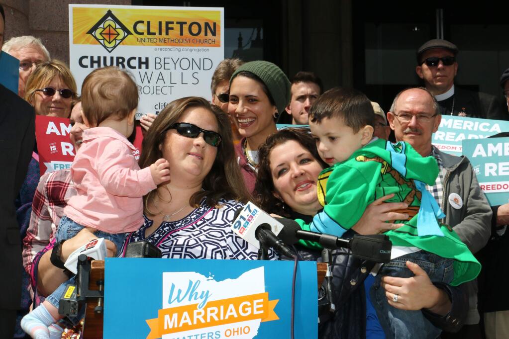 Pam, left, and Nicole Yorksmith, married in California, hold their children, Orion, ten months, and Grayden, 4, from left to right, as they speak to supporters during a send-off event Friday, April 24, 2015, in support of plaintiffs in gay marriage cases that will be argued before the U.S. Supreme Court, in Cincinnati. They are among the 19 men and 12 women whose same-sex marriage cases from those two states, plus Michigan and Tennessee, will be argued at the Supreme Court on Tuesday, April 28. (AP Photo/Tom Uhlman)