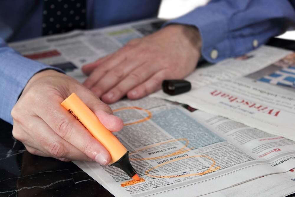 A job seeker marks jobs he’s interested in in a newspaper’s classified section. (Stock photo)