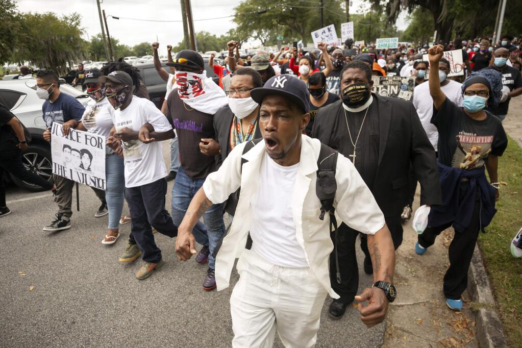 Malik Muhammad, center, joins a group of people marching from the Glynn County Courthouse in downtown to a police station after a rally to protest the shooting of Ahmaud Arbery, Saturday, May 16, 2020, in Brunswick, Ga. (AP Photo/Stephen B. Morton)