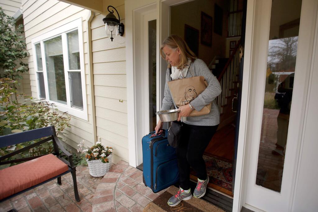 Preparing for a business trip, Kaiser Permanente surgeon Dr. Patricia May carries her suitcase out of her friends' home where her family is staying after their own home was destroyed by the Tubbs Fire, in Santa Rosa, California on Thursday, October 19, 2017. (Alvin Jornada / The Press Democrat)