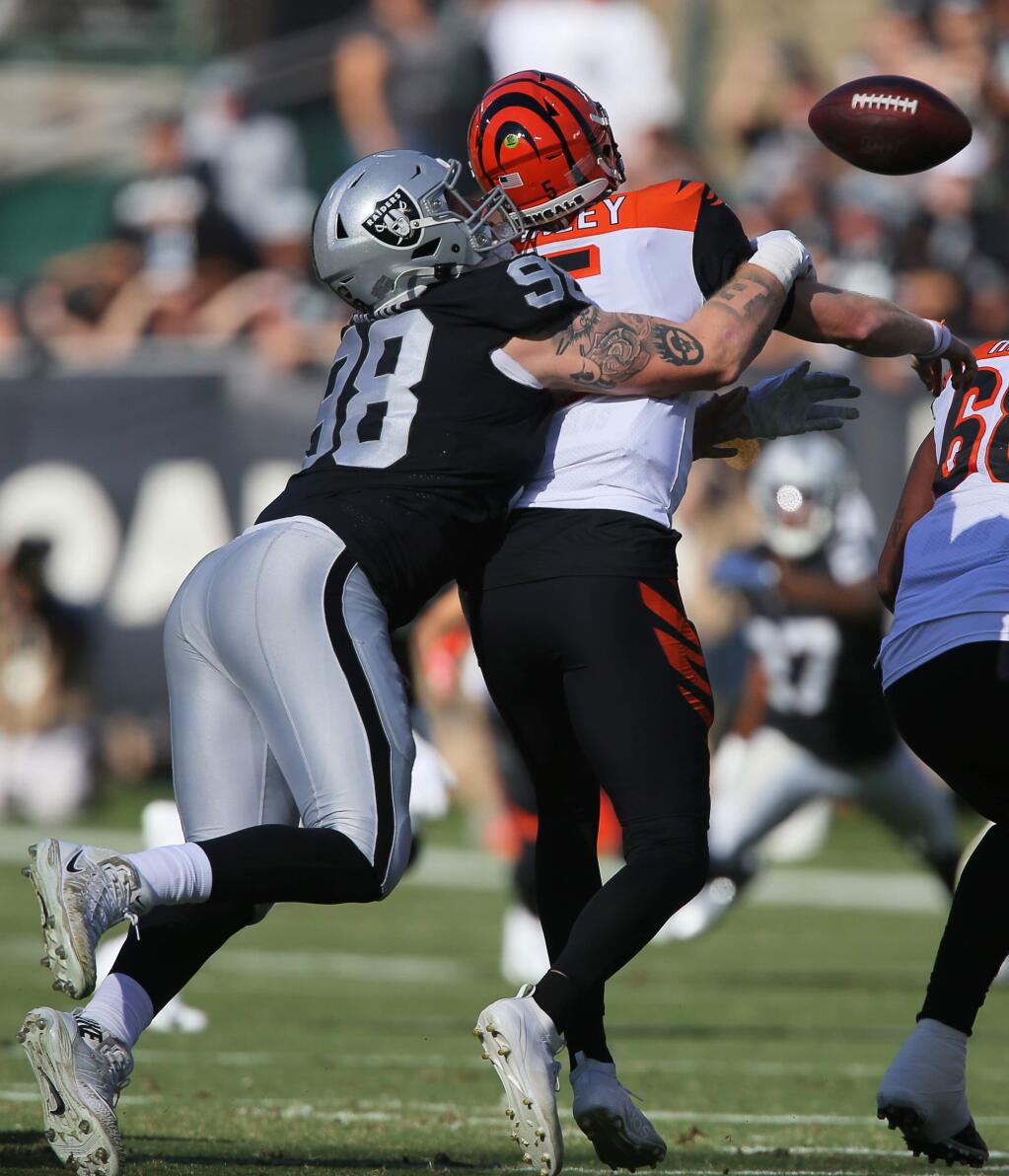 Oakland Raiders defensive end Maxx Crosby strips the ball from Cincinnati Bengals quarterback Ryan Finley during their game in Oakland on Sunday, November 17, 2019. (Christopher Chung/ The Press Democrat)