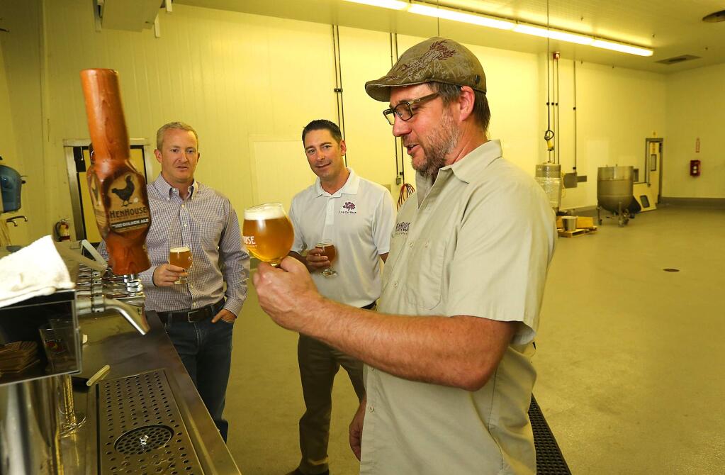 JOHN BURGESS / The Press Democrat) HenHouse Brewing Co. co-owner Scott Goyne, right, pours a beer for Live Oak Bank senior lenders Randall Behrens, center, and Tracy Sheppard at the company's new production facility in Santa Rosa.