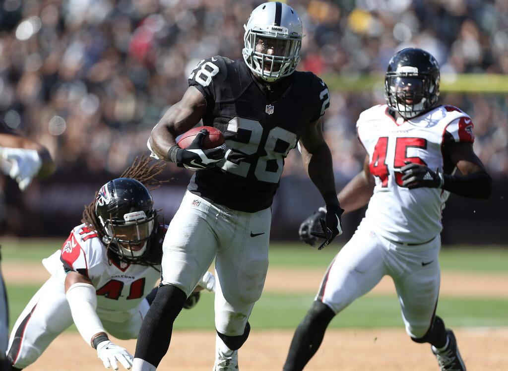 Oakland Raiders running back Latavius Murray makes a big gain against Atlanta Falcons defenders Philip Wheeler and Deion Jones during their game in Oakland on Sunday, September 18, 2016. The Raiders lost to the Falcons 35-28. (Christopher Chung / The Press Democrat)