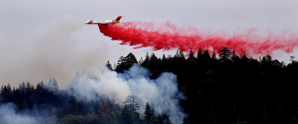 A firefighting plane drops a load of fire retardant over a smoldering hillside Tuesday, Sept. 15, 2015, in Middletown, Calif. The fire that sped through Middletown and other parts of rural Lake County, less than 100 miles north of San Francisco, has continued to burn since Saturday despite a massive firefighting effort. (AP Photo/Elaine Thompson)