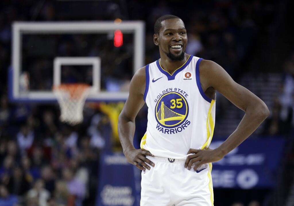 Golden State Warriors' Kevin Durant smiles during a break in play during the second half of an NBA basketball game against the Dallas Mavericks Thursday, Dec. 14, 2017, in Oakland, Calif. (AP Photo/Marcio Jose Sanchez)
