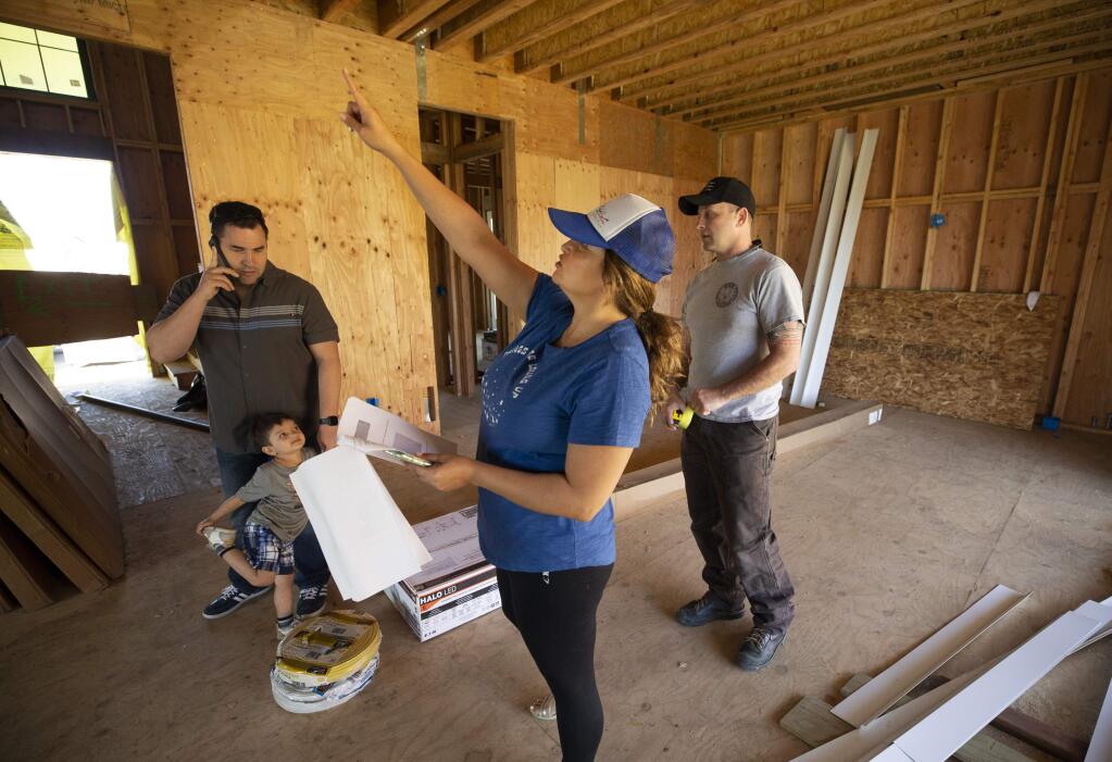 Cynthia Hermosilllo points out where to hang pendant light to her contractor Eric Runft, right, and her husband Shawn while touring their Coffey Park home under consttruction on Thursday. (photo by John Burgess/The Press Democrat)
