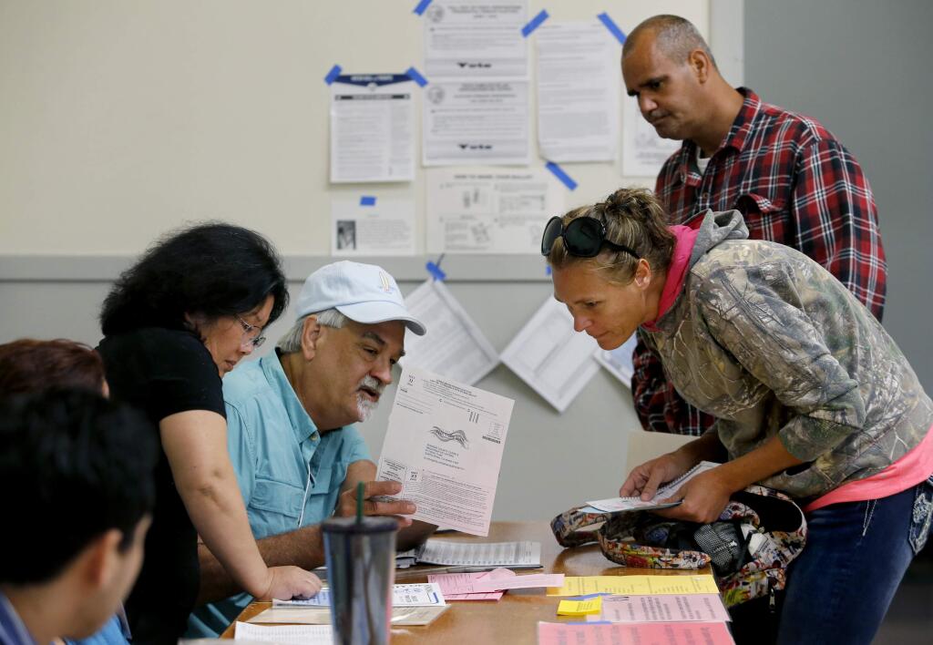 Maggie Breeden, joined by her friend Shawndell Garrison, gets help from election worker, Chris Carrieri, left, to find their polling location. Photo taken at the Santa Rosa Veterans Memorial Building in Santa Rosa, on Tuesday, June 7, 2016. (BETH SCHLANKER/ The Press Democrat)