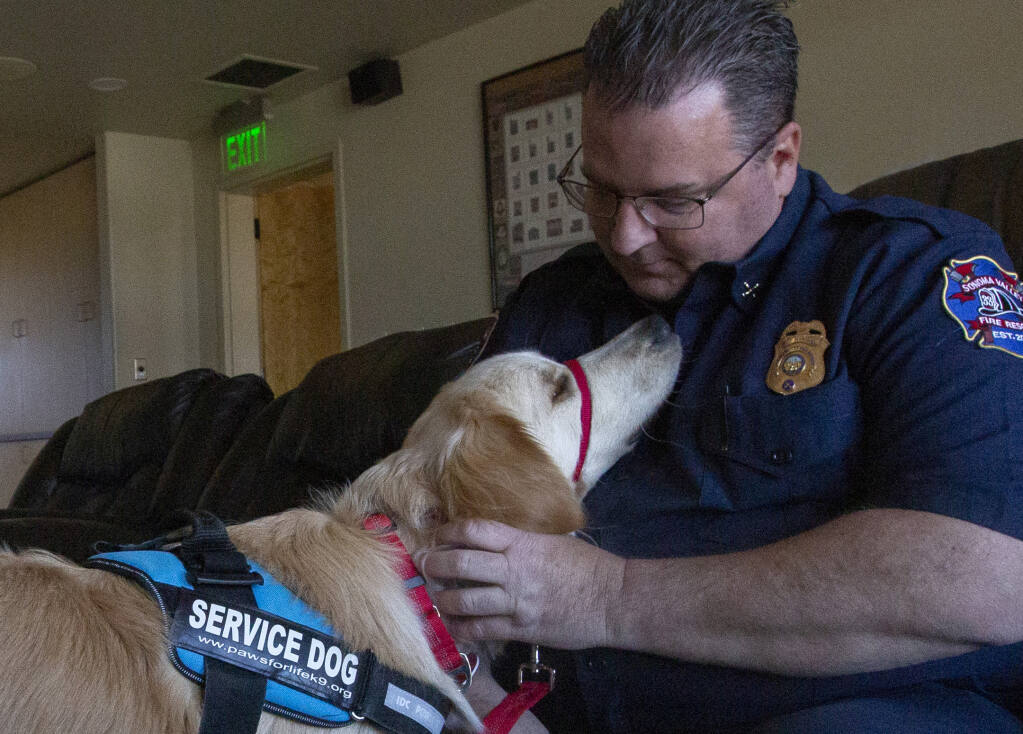 Fire Marshal Trevor Smith bonds with Koda, the therapy dog, at the Al Mazza Fire Station on Second Street West on Monday, April 3, 2023.  (Robbi Pengelly/Index-Tribune)
