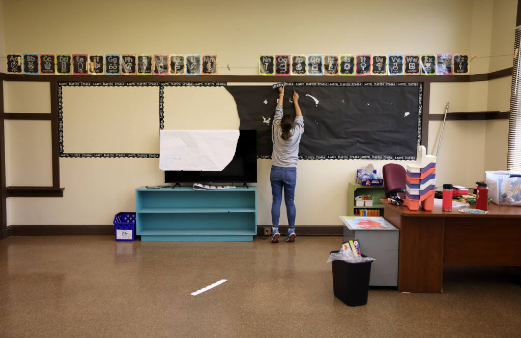 Sixth grade teacher Brenna Pourroy, takes old elementary school age decorations down in her classroom at the new Mayacamas Charter Middle School, formerly St. John the Baptist Catholic School, in Napa, Tuesday, Aug. 8, 2023. (Beth Schlanker / The Press Democrat file)