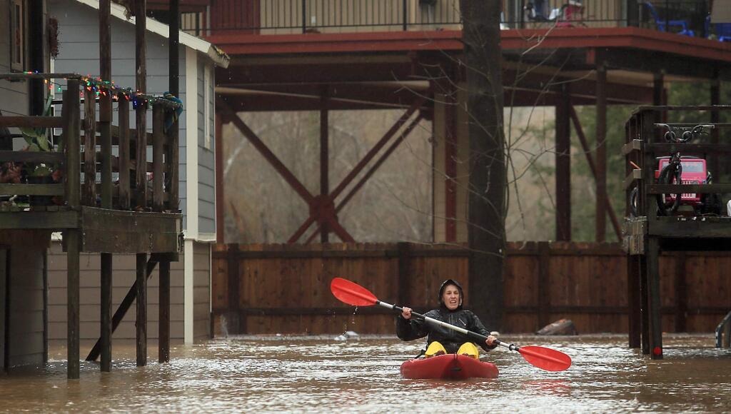 Elizabeth Hamilton, a resident of Sycamore Court Apartments, kayaks around the complex looking to see if anyone needed a lift out of the flood waters in Guerneville, Tuesday Jan. 10, 2017. (Kent Porter / The Press Democrat) 2017