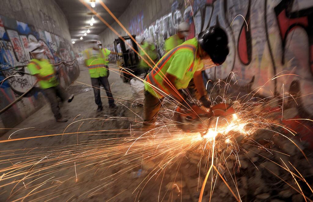 Sergei Yarushin slices through rebar and concrete as workers dismantle damaged portions of Santa Rosa's underground water diversion tunnel, Monday Sept. 11, 2017 under E Street. (Kent Porter / The Press Democrat) 2017