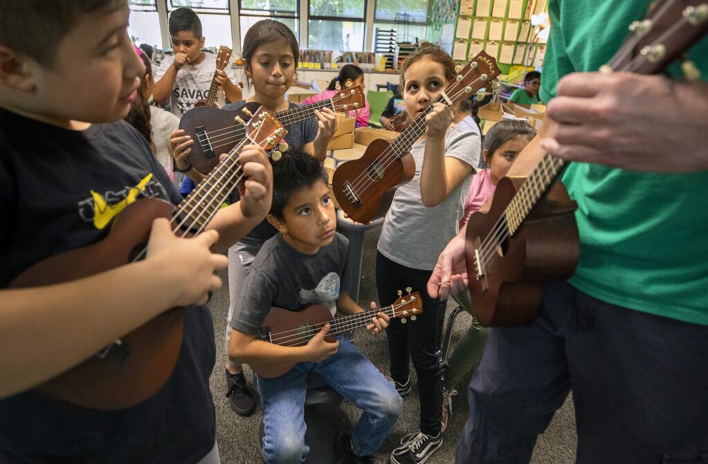Clockwise from left, third graders Danny Avalos, Fatima Arevalo, Yuliana Miranda and Anthony Ayala-Sanchez learn the fingering for the 'Evil G-note' on the ukulele from teacher Steve Ciaffa at Roseland elementary school. (photo by John Burgess/The Press Democrat)