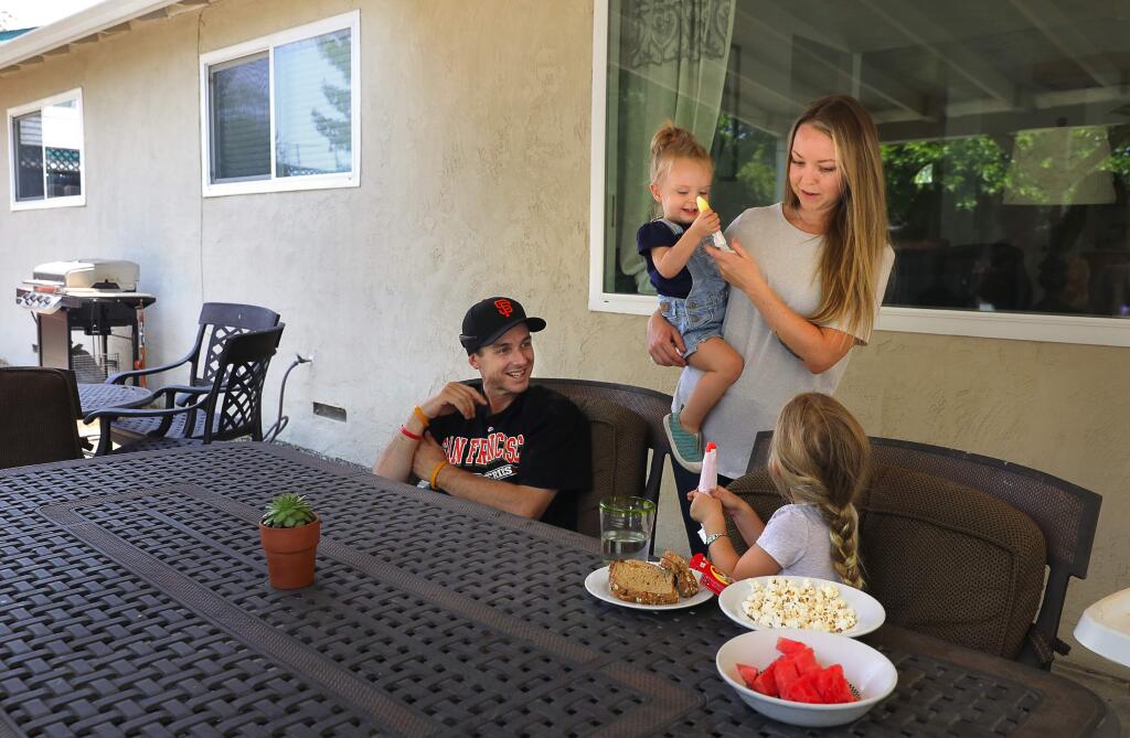 Anthony and Laura Salvato, with their daughters Emma, 2, and Grace, 4, have snacks in the backyard of their new Rincon Valley area home, in Santa Rosa on Tuesday, July 31, 2018.(Christopher Chung/ The Press Democrat)