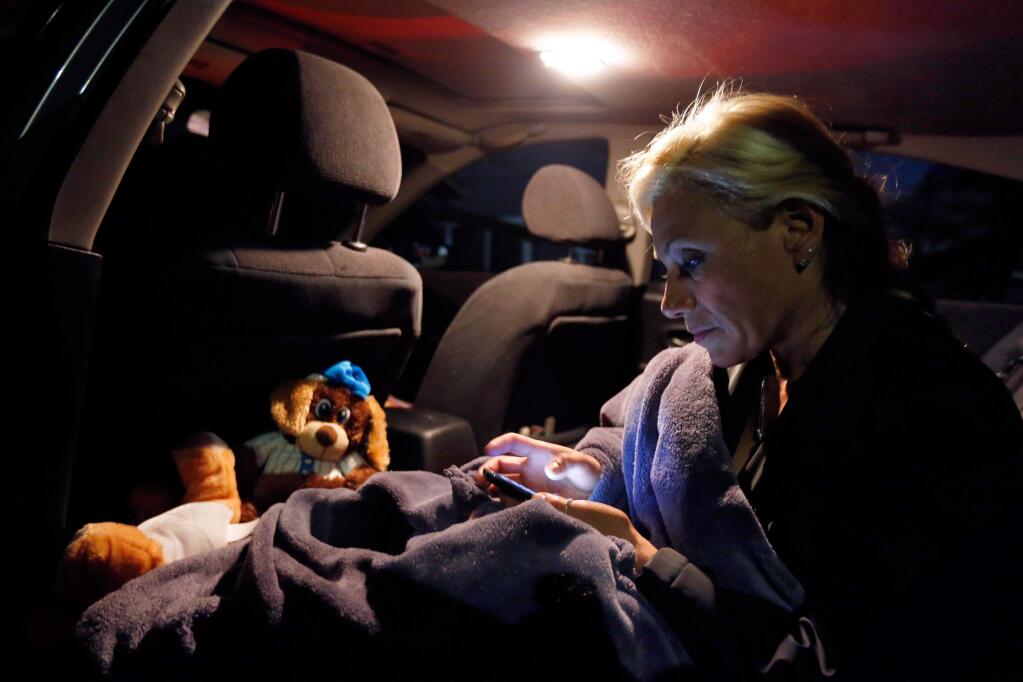 Evicted from her Santa Rosa apartment, Ruth Lopez Contreras checks her cell phone before she goes to sleep in her car while parked in a friend's driveway in Santa Rosa, California on Wednesday, June 22, 2016. (Alvin Jornada / The Press Democrat)