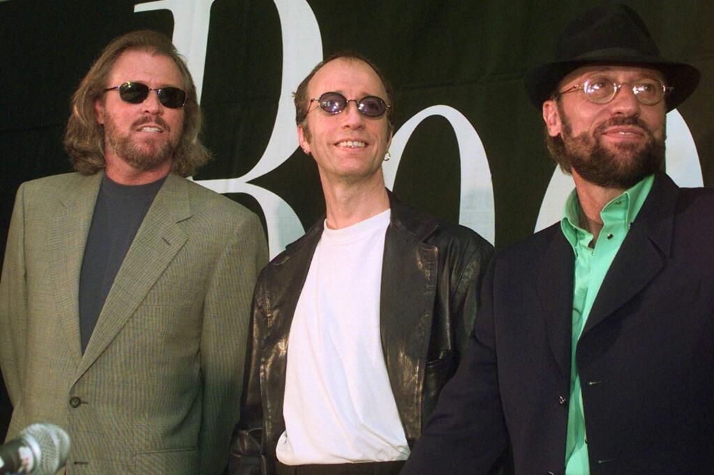 FILE - This July 29, 1998 file photo shows brothers Barry, Robin and Maurice Gibb, left to right, of the pop group the Bee Gees during a news conference in Miami Beach, Fla. The Recording Academy and CBS will pay tribute to the Bee Gees two days after the Grammys with a concert featuring a range of artists, including Celine Dion, Andra Day, John Legend and Keith Urban. The concert will be taped Feb. 14 at the Microsoft Theater, to be broadcast on CBS later this year. (AP Photo/Marta Lavandier, File)