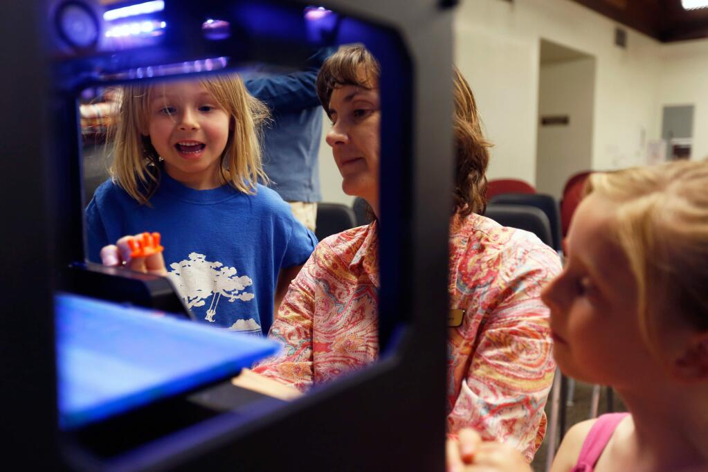 Librarian Diana Spaulding, center, shows a small stool made by a 3-D printer to Kaia Steiner, age 5, left, and her sister Ella Steiner, age 8 during a 3-D printing workshop at the Petaluma Regional Library in Petaluma, California, on August 26, 2015. (Alvin Jornada / The Press Democrat)