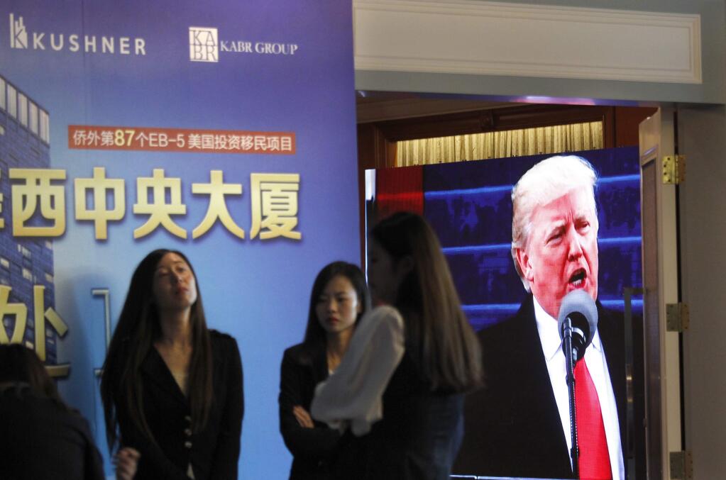 A projector screen shows footage President Donald Trump during an event in Shanghai promoting EB-5 investments in a Kushner Companies development project. (Associated Press)