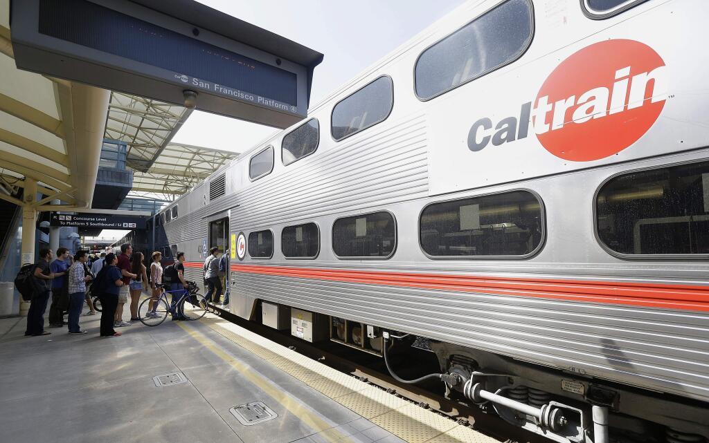 FILE - In this July 1, 2013, file photo, commuters board a Caltrain train at the Caltrain and Bay Area Rapid Transit station in Millbrae, Calif. The Trump administration has agreed to fully fund a $650 million federal grant for electrification of a San Francisco Bay Area train system that would also help California's high-speed rail project. (AP Photo/Jeff Chiu, File)