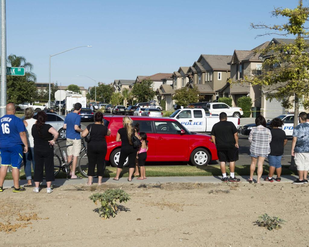 A small crowd gathers near a home where five people were found dead, Saturday, July 18, 2015, in Modesto, Calif. A Modesto police spokeswoman said officers responding to a request to conduct a welfare check discovered the bodies of three children and two adults Saturday afternoon. (John Westberg/The Modesto Bee via AP) NO SALES, MAGS OUT, TV OUT MANDATORY CREDIT