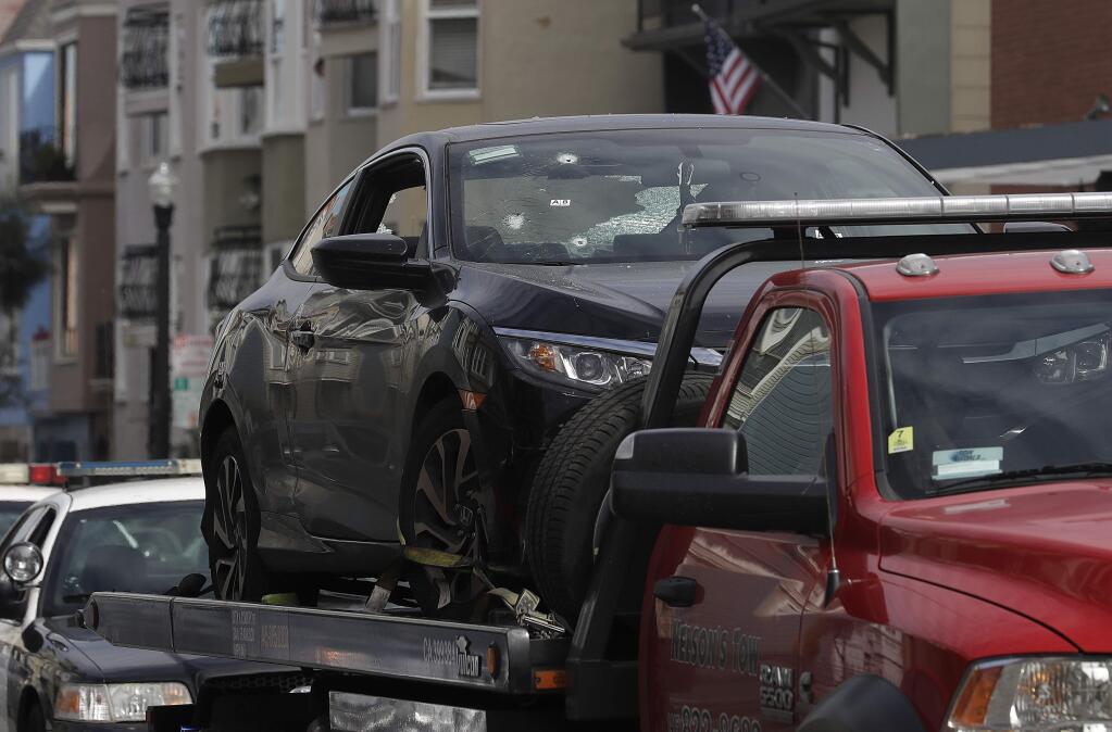 Bullet holes appear on a vehicle as it is towed away in San Francisco, Wednesday, March 7, 2018. San Francisco police say officers who were investigating an armed robbery shot and killed a man who was hiding in the trunk of a car on Tuesday night. (AP Photo/Jeff Chiu)