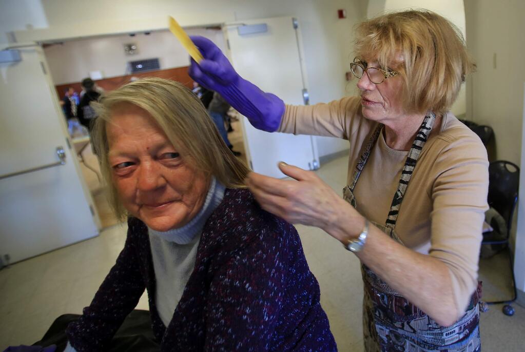 Kathy Plumb, who is homeless, has her hair combed by volunteer Emily Brawley after she took a shower Thursday at at Veterans Memorial Hall in Guerneville.