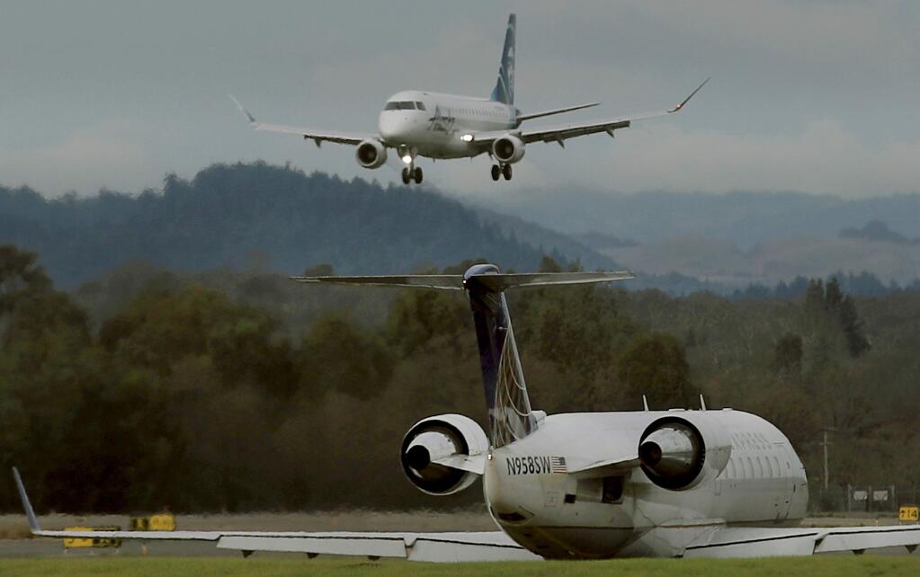 An Alaska/Horizon Airlines flight lands as an United Express plane taxis into position on Tuesday, Dec. 24, 2019 at the Charles M. Schulz Sonoma County Airport in Santa Rosa. (Kent Porter / The Press Democrat) 2019