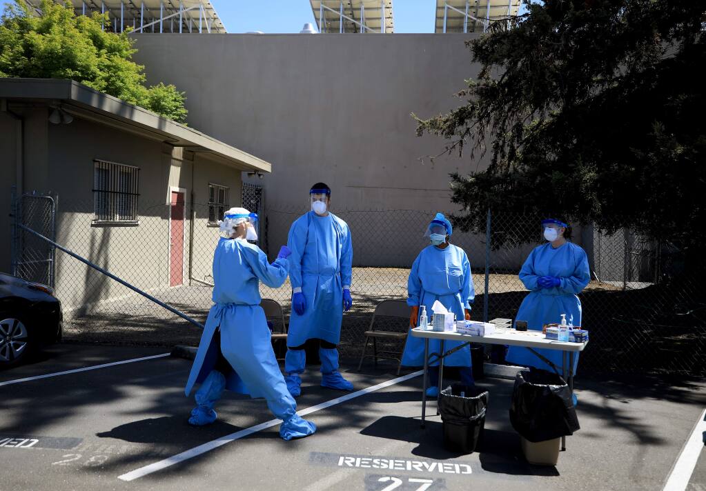 Sonoma County Public Health nurses, from left, Maggie Wideau, Jacob Soled, Sylvia Brown and Katy Jenkins take a break from the heat of the day during a drive up coronavirus testing and tracing clinic, Wednesday, April 22, 2020 in Santa Rosa. (Kent Porter / The Press Democrat) 2020