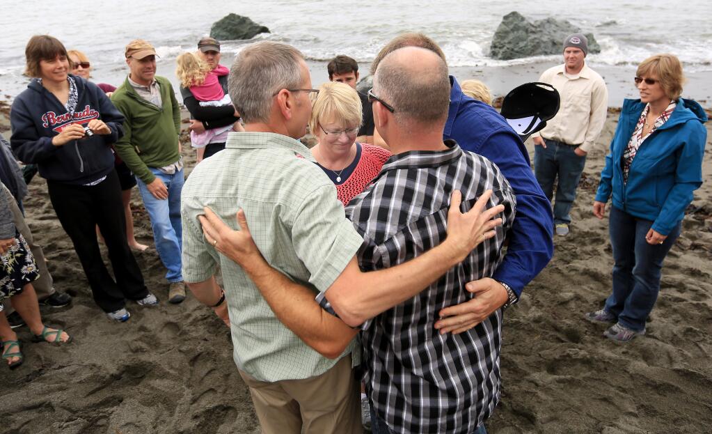 The Cutshalls, left, embrace Sonoma County Sheriff's Sgts. Tim Duke and Dave Thompson, right, on Friday, Aug. 15, 2014 as they mourn Lindsay Cutshall and her fiance, Jason Allen, at Fish Head Beach. The two were slain there in 2004. (KENT PORTER/PD)