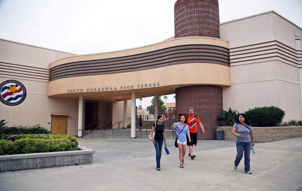 People walk past South Pasadena, Calif., High School Tuesday, Aug. 19, 2014, after authorities announced the arrest of two high school students suspected of planning a massacre at the school after investigators monitored their Internet activities. (AP Photo/Nick Ut)