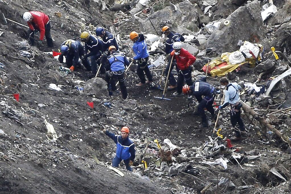 Rescue workers work on debris of the Germanwings jet at the crash site near Seyne-les-Alpes, France, Thursday, March 26, 2015. The co-pilot of the Germanwings jet barricaded himself in the cockpit and intentionally rammed the plane full speed into the French Alps, ignoring the captains frantic pounding on the cockpit door and the screams of terror from passengers, a prosecutor said Thursday. In a split second, he killed all 150 people aboard the plane. (AP Photo/Laurent Cipriani)