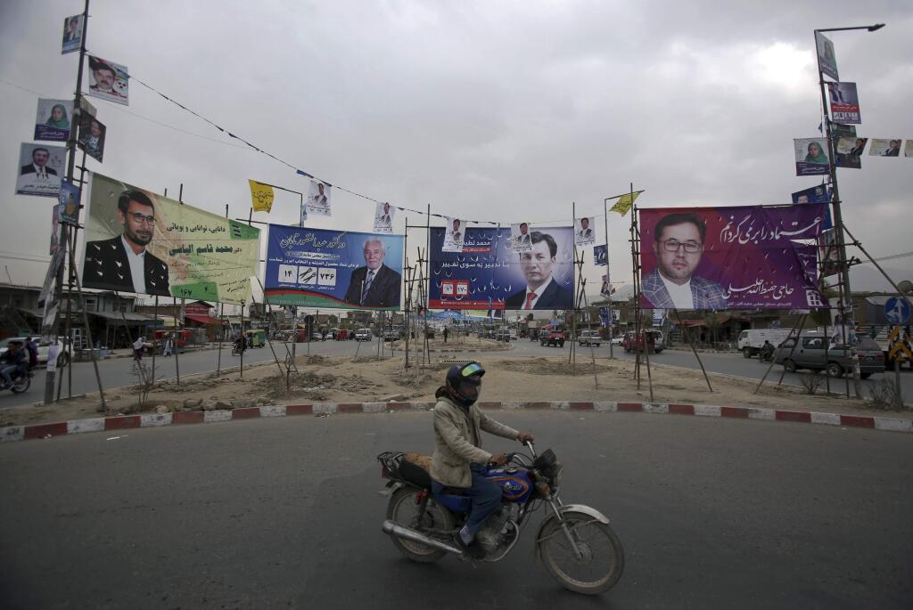 In this Tuesday, Oct. 16, 2018, photo, a man rides his motorbike in front of campaign posters for parliamentary candidates, in Kabul, Afghanistan. Afghans will return to the polls on Saturday, hoping to bring change to a corrupt government that has lost nearly half the country to the Taliban. In the eight years since Afghanistan last held parliamentary elections a resurgent Taliban has carried out near-daily attacks, seizing large swathes of the countryside and threatening major cities. (AP Photo/Rahmat Gul)