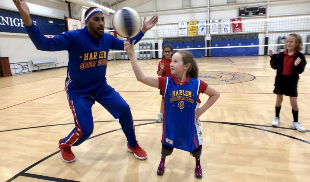 Lilly Biagini, whose prosthetic legs were lost in the Tubbs fire, twirls a ball on her finger as she meets up with 'best friend' Harlem Globetrotter Zeus McClurkin recently in her new town of Dallas. McClurkin had met Lilly last November in Healdsburg when he was appearing with the team in Oakland.