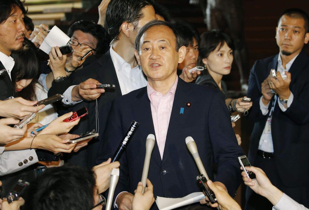 Japan's Chief Cabinet Secretary Yoshihide Suga, center, answers a reporter's question on an eruption of a volcano in southern Japan, at prime minister's official residence in Tokyo Friday, May 29, 2015. Mount Shindake on Kuchinoerabu island erupted in spectacular fashion on Friday, spewing towering black-gray clouds into the sky. Authorities ordered residents to evacuate the island. (Kyodo News via AP) JAPAN OUT, MANDATORY CREDIT