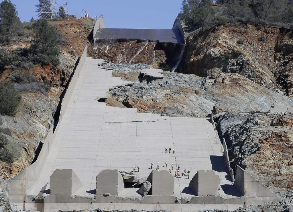 FILE- In this Feb. 28, 2017 file photo, officials inspect Oroville Dam's crippled spillway in Oroville, Calif. California is asking owners of about 70 aging dams, some dating back to the Gold Rush, to thoroughly inspect their spillways and underlying rock, as part of stepped-up inspections in the wake of the surprise spillway failures at the nation's highest dam. (AP Photo/Rich Pedroncelli, file)