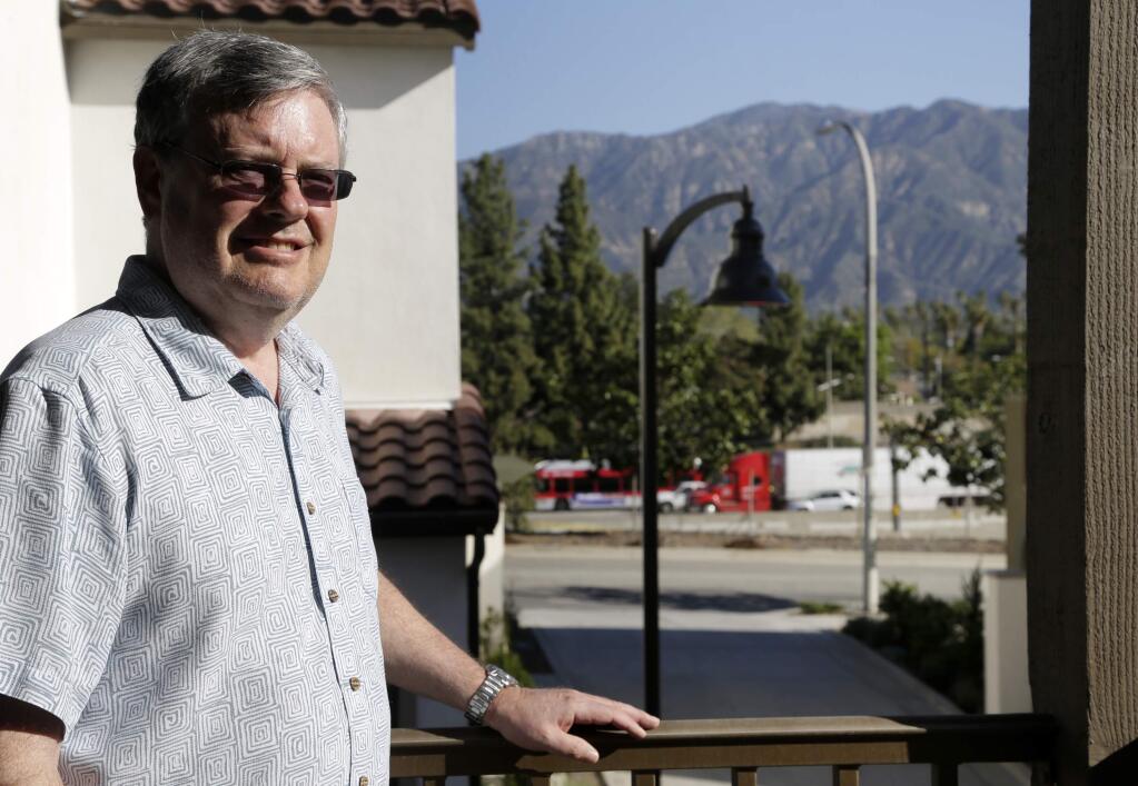 In this Thursday, March 17, 2016, photo, Robert Leviton poses for a photo on the balcony of his townhouse in Pasadena, Calif. The traffic on the stretch of highway, background, that runs alongside his complex creates a persistent din and is visible from any of his townhome's north-facing windows. Leviton knew it would be like this when he bought the two-bedroom unit for $666,000 last summer. (AP Photo/Nick Ut)