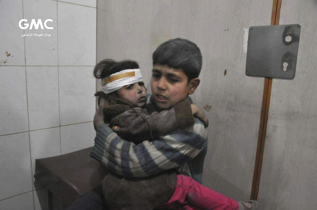 This photo released on Wednesday Feb. 21, 2018 provided by the Syrian anti-government activist group Ghouta Media Center, which has been authenticated based on its contents and other AP reporting, shows two Syrian kids who were wounded during airstrikes and shelling by Syrian government forces, sit at a makeshift hospital, in Ghouta, suburb of Damascus, Syria. New airstrikes and shelling on the besieged, rebel-held suburbs of the Syrian capital killed at least 10 people on Wednesday, a rescue organization and a monitoring group said. (Ghouta Media Center via AP)