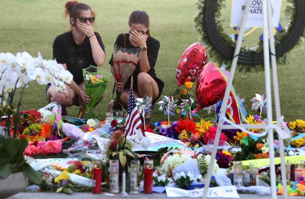 Kelli Cantu 24, left and Soe Aponte, 23, of Orlando become emotional Tuesday, June 14, 2016, as they visit a growing memorial at the The Dr. Phillips Center for the victims of the mass shooting at the Pulse Nightclub. (Red Huber/Orlando Sentinel via AP)