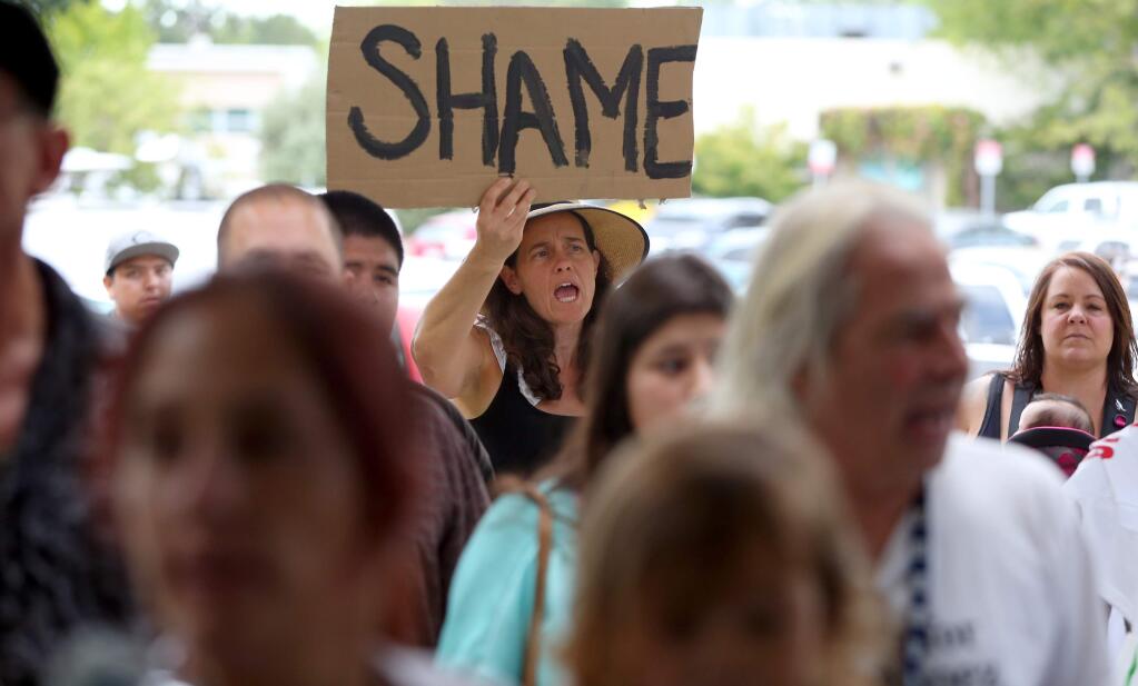 Liz Cozine protests outside of where district attorney Jill Ravitch held a press conference at the Permit and Resources Management Department in response to the Andy Lopez decision Monday, July 7, 2014. (Christopher Chung/The Press Democrat)