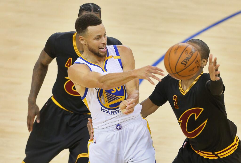 Golden State Warriors guard Stephen Curry passes out of a double team by Cleveland Cavaliers defenders Kyrie Irving and Iman Shumpert during Game 2 of the NBA Finals in Oakland on Sunday, June 4, 2017. The Warriors defeated the Cavaliers 132-113. (Christopher Chung / The Press Democrat)