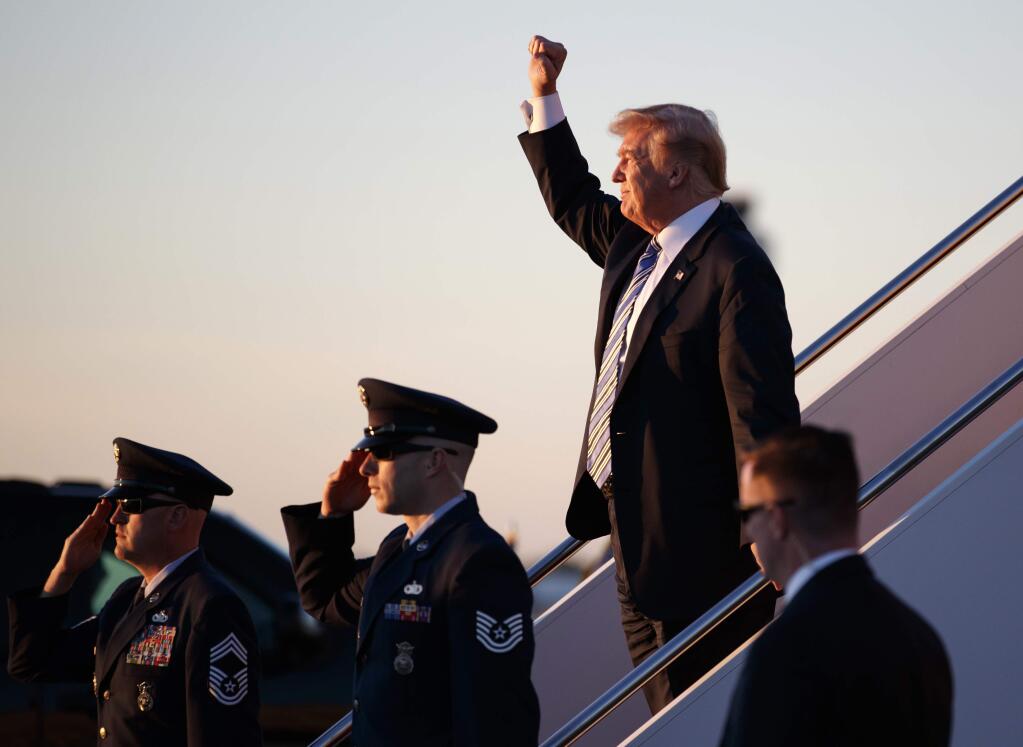 President Donald Trump gestures to people cheering him across the tarmac as he, arrives on Air Force One with first lady Melania Trump and their son Barron Trump at Palm Beach International Airport, in West Palm Beach, Fla., Friday, March 23, 2018. (AP Photo/Carolyn Kaster)