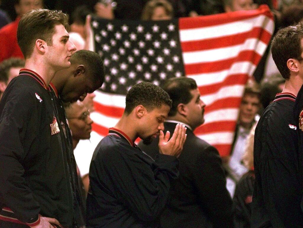 In this March 15, 1996 file photo, Denver Nuggets guard Mahmoud Abdul-Rauf stands with his teammates and prays during the national anthem before a game against the Chicago Bulls in Chicago. This was Abdul-Rauf's first game back since he was suspended by the NBA on March 12, 1996, for refusing to participate in the national anthem pregame ceremony. (AP Photo/M. Spencer Green, File)
