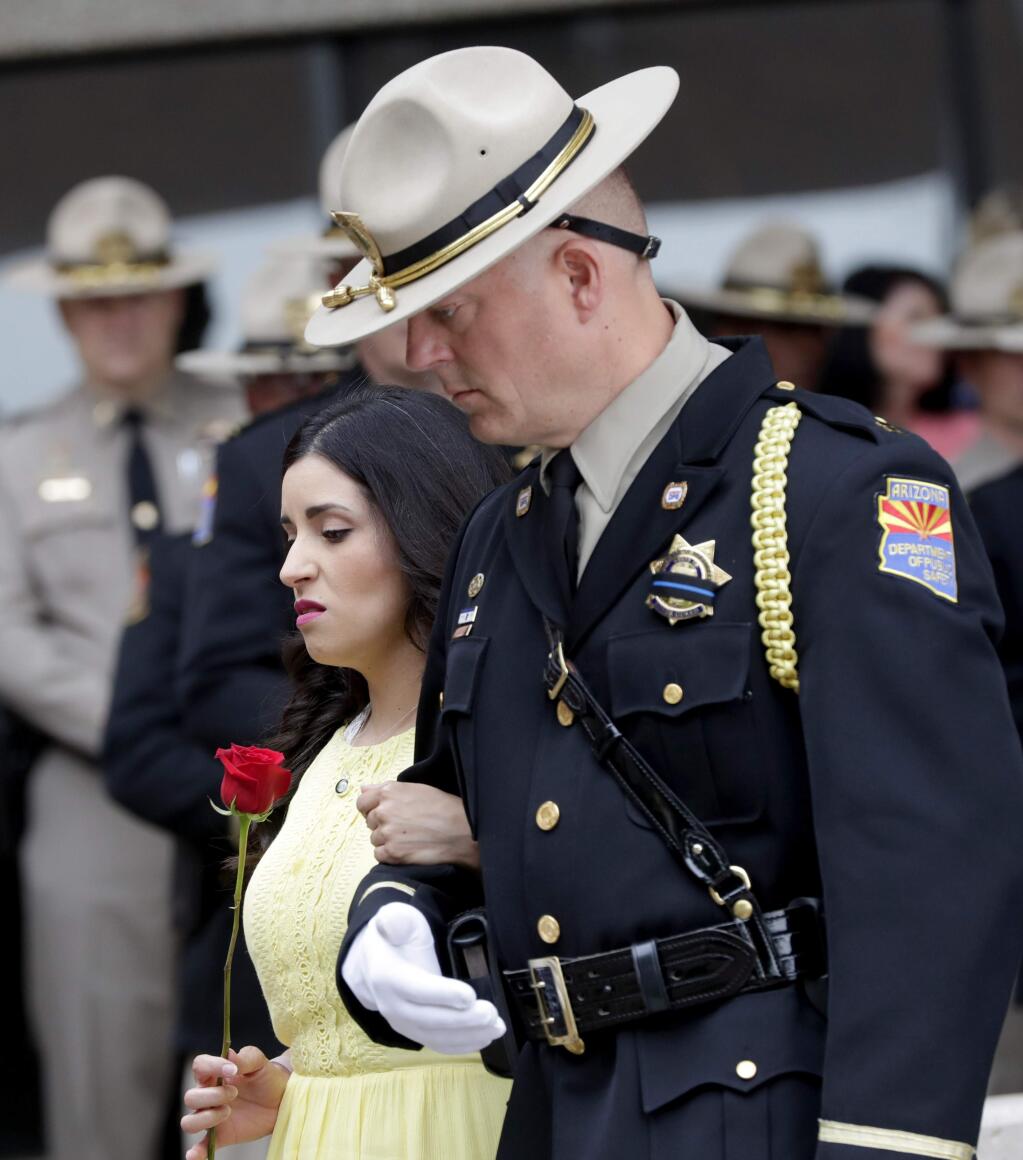A family member of a fallen DPS Trooper is escorted to the memorial wall during the annual Department of Public Safety Officer Memorial Ceremony, Monday, May 6, 2019, in Phoenix. During the ceremony a plaque was added for 24-year-old Tyler Edenhofer to be displayed with the 29 other troopers who have been killed on the job since 1958. (AP Photo/Matt York)