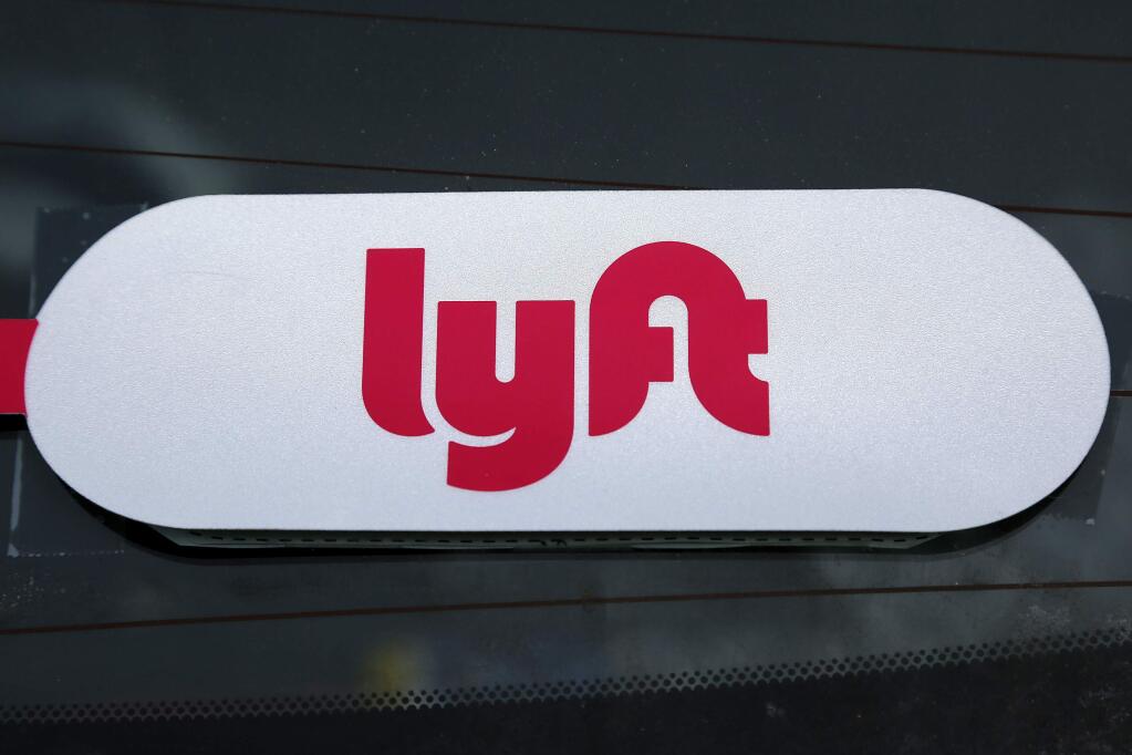 FILE - This Jan. 31, 2018 file photo shows a Lyft logo on a Lyft driver's car in Pittsburgh. (AP Photo/Gene J. Puskar, File)