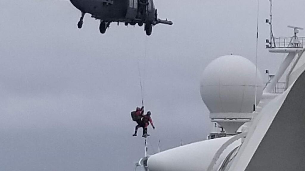 In this photo provided by Michele Smith, a National Guard helicopter delivering virus testing kits lowers crew down to the Grand Princess cruise ship Thursday, March 5, 2020, off the California coast. Scrambling to keep the coronavirus at bay, officials ordered a cruise ship with about 3,500 people aboard to hold off the California coast Thursday until passengers and crew could be tested, after a traveler from its previous voyage died and at least one other became infected. Princess Cruises says fewer than 100 of those aboard have been identified for testing. (Michele Smith via AP)