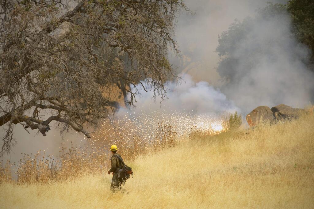 Hot Shot crews from Truckee use incendiary devices to start backfires to help contain the County Fire along Highway 129 near Lake Berryessa in Yolo County, California, Tuesday, July 3, 2018. (Randall Benton/The Sacramento Bee via AP)