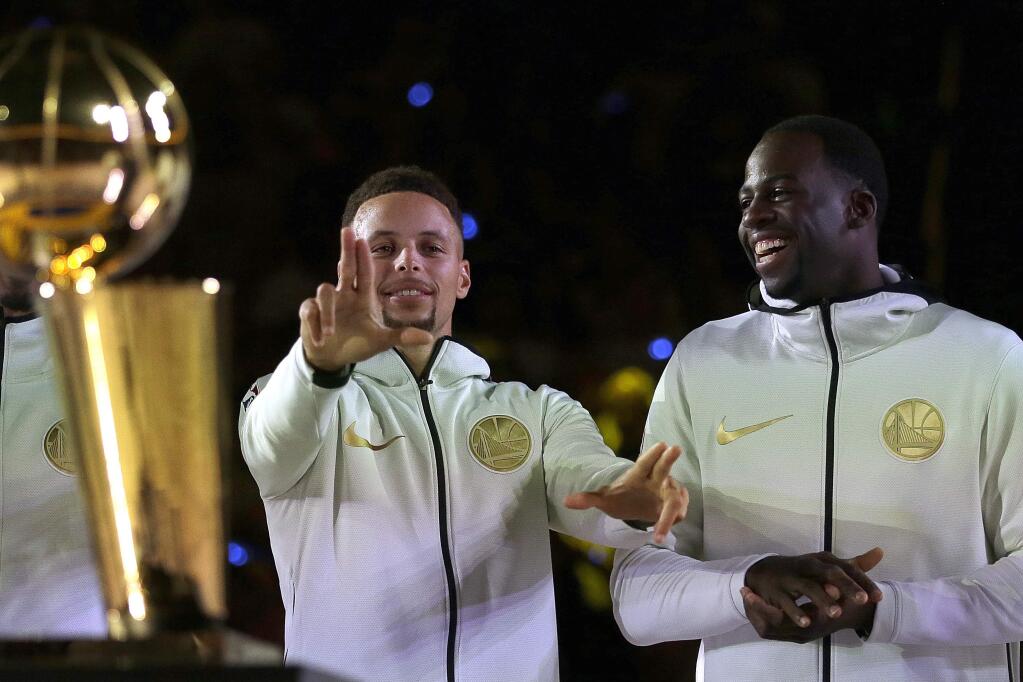 Golden State Warriors' Stephen Curry, left, gestures beside Draymond Green during an NBA championship ring ceremony prior to a game against the Houston Rockets Tuesday, Oct. 17, 2017, in Oakland. (AP Photo/Ben Margot)