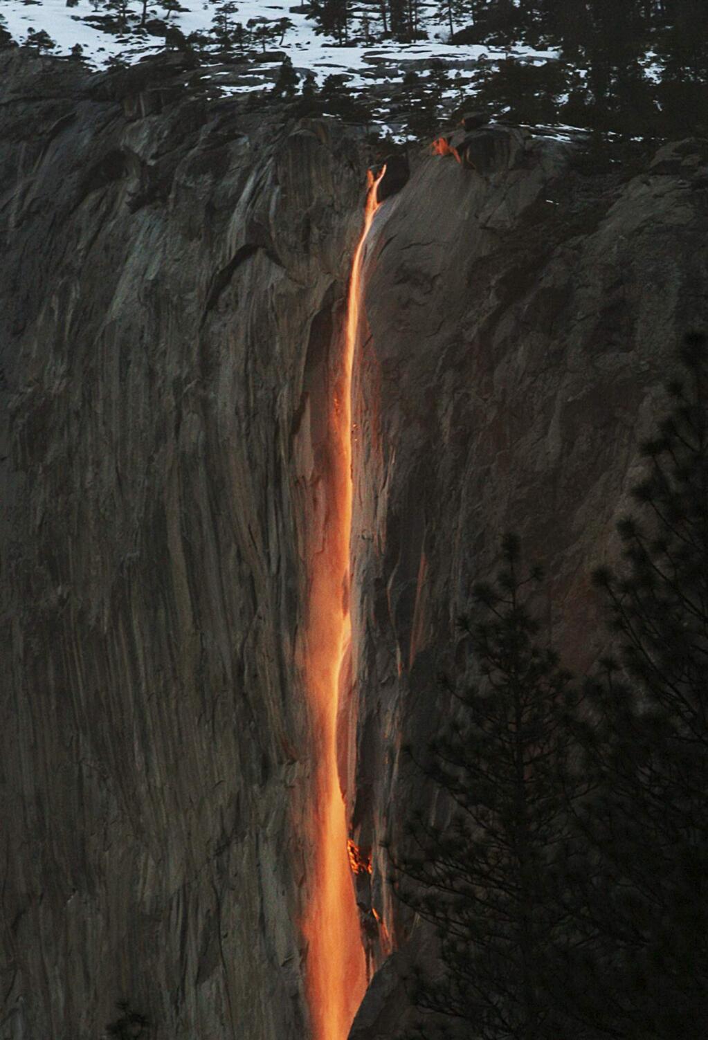FILE - In this Feb. 16, 2010, file photo, a shaft of sunlight creates a glow near Horsetail Fall, in Yosemite National Park, Calif. Mother Nature is again putting on a show at California's Yosemite National Park, where every February the setting sun draws a narrow sliver on a waterfall to make it glow like a cascade of molten lava. The phenomenon known as “firefall” draws scores of photographers to the spot, which flows down the granite face of the park's famed rock formation, El Capitan. (Eric Paul Zamora/The Fresno Bee via AP, File)
