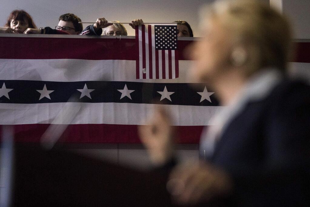 A woman holds an American flag as she listens to Democratic presidential candidate Hillary Clinton speak at a rally at the Downtown Toledo Train Station in Toledo, Ohio, Monday, Oct. 3, 2016. (AP Photo/Andrew Harnik)