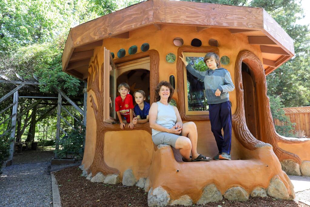 Veronica Vuksich, with her sons Alex Armstrong, left, Galen Armstrong, both 9, and Oliver Armstrong, 12, have a new fanciful earthen cob playhouse, built by Miguel Elliott of Living Earth Structures, in the backyard of their Santa Rosa home.(Christopher Chung/ The Press Democrat)